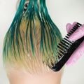 High-angle shot of hairstylist combing wet green and discolored hair while shampooing in sink