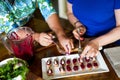 High angle shot of the hands of two women preparing bruschettas in a white plate on the table Royalty Free Stock Photo