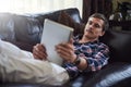 Surfing on his sofa. High angle shot of a handsome young man using his tablet while sitting on the sofa at home. Royalty Free Stock Photo