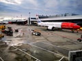 High-angle shot of a landing white and red airplane at Copenhagen airport, gloomy sky background