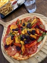 High angle shot of a large pizza on a wooden foote with vegetables