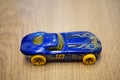 High angle shot of a Mattel Hot Wheels blue race car toy on a wooden surface