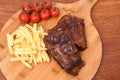 High angle shot of meat slices, french fries, and tomatoes on a kitchen board Royalty Free Stock Photo