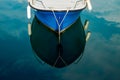 High-angle shot of a moored blue fishing boat reflecting in the water