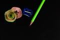 High angle shot of one green pencil and two round shavings with a sharpener on black background Royalty Free Stock Photo