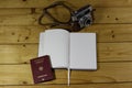 High angle shot of an open notebook next to a passport and a camera on a wooden surface Royalty Free Stock Photo