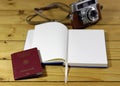 High angle shot of an open notebook next to a passport and a camera on a wooden surface Royalty Free Stock Photo