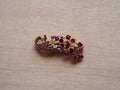 High angle shot of a peacock-shaped hairpin with purple and pink gemstones on the table