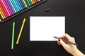 High angle shot of a person drawing on a white paper with color pens on a black surface