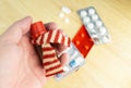 High angle shot of a person holding a bottle of medicine over some pills on a wooden surface Royalty Free Stock Photo