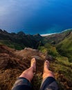 High angle shot of a person sitting on a cliff and looking down on the Napali Coast, Kauai, Hawaii Royalty Free Stock Photo