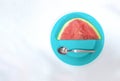High angle shot of a piece of sliced watermelon on a blue plate with a spoon on a white background Royalty Free Stock Photo