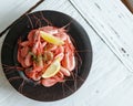 High angle shot of a plate of Botan shrimps with lemon on a white wooden surface