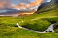 High angle shot of a river in the middle of grassy hills near a mountain under a cloudy sky Royalty Free Stock Photo