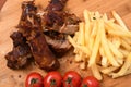 High angle shot of roasted meat on a wooden board with french fries and tomatoes on it Royalty Free Stock Photo