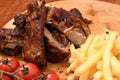 High angle shot of roasted meat on a wooden board with french fries and tomatoes on it Royalty Free Stock Photo