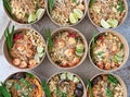 High angle shot of servings of delicious noodles with salads, lime, greens, and crumbs