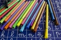 High angle shot of a set of colorful pens on a blue surface with the alphabet on it Royalty Free Stock Photo