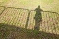 High angle shot of the shadow of a person standing next to a fence Royalty Free Stock Photo