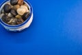 High angle shot of small colorful rocks in a china bowl on a blue surface Royalty Free Stock Photo