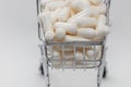 High angle shot of a small shopping cart full of white pills. White background. Close up shot. Shopping online, buying medicine, Royalty Free Stock Photo