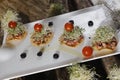 High angle shot of small toast pieces with salmon, cherry tomatoes and greens