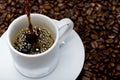 High angle shot of some coffee being poured into a white cup on a surface full of coffee beans Royalty Free Stock Photo