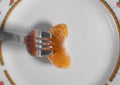 High angle shot of a tangerine and a fork on a plate