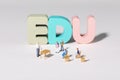 High angle shot of teacher and student figurines standing around EDU letters