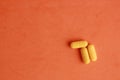 High angle shot of three yellow pills isolated on n orange surface Royalty Free Stock Photo
