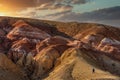 High angle shot of a tourist climbing massive red mountains in Kyzyl-Chin valley, also called Mars valley. Beautiful cloudy sunset