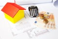 High angle shot of a toy house, banknotes, coins, a calculator and house plans- real estate concept Royalty Free Stock Photo