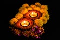 High angle shot of two clay lamps glowing on rose petals with yellow flowers over the black background. faith and tradition Royalty Free Stock Photo