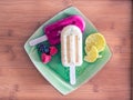 High angle shot of two delicious popsicles with fruits in a green plate on a wooden table Royalty Free Stock Photo