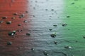 High angle shot of water drops of a black surface with reflection of red, white and green lights Royalty Free Stock Photo