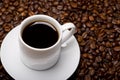 High angle shot of a white cup of black coffee on a surface full of coffee beans Royalty Free Stock Photo