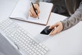 High angle shot of woman hands working with gadgets. Cropped shot of modern female holding smartphone while writing plan Royalty Free Stock Photo