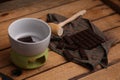 High angle shot of a wooden small mallet near a bar of dark chocolate and a bowl of chocolate