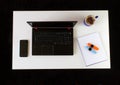 High angle shot of a work desk with a laptop, a cup of coffee, mobile phone, notepad, and headphones Royalty Free Stock Photo