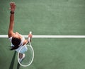 Game on. High angle shot of a young woman serving a ball while playing tennis on a court. Royalty Free Stock Photo