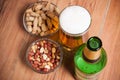 High Angle Still Life View of Glass of Cold Ale, Bottle of Beer, Bowl of Peanuts and Bottle on Rustic Wooden Table with Copy Spa