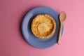 High angle top view closeup shot of cheese quiche with a wooden spoon on a pink table