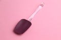 High angle top view closeup shot of a silicone spatula with a glass handle on a pink table