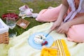 female cutting delicious cheese with olives during picnic with strawberry in park.