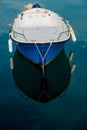 High-angle vertical shot of a moored blue fishing boat reflecting in the water