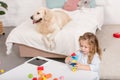 high angle view of adorable kid playing with educational cubes, cute dog lying on bed