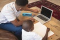 High angle view of African American father helping his son with homework on laptop at table Royalty Free Stock Photo