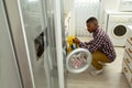 Man putting clothes in washing machine in kitchen at home Royalty Free Stock Photo