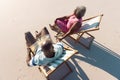High angle view of african american senior couple holding hands and sitting on deckchairs at beach Royalty Free Stock Photo