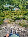 High angle view from altitude of a tourist POV shooting his feet standing on the edge of a cliff above the Saharna Monastery,